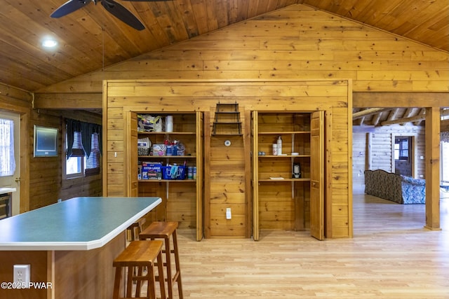 kitchen featuring a center island, lofted ceiling, wooden walls, ceiling fan, and light hardwood / wood-style floors