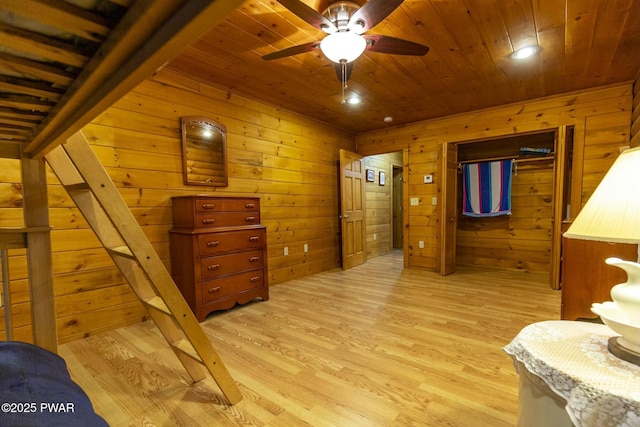 bedroom featuring light hardwood / wood-style floors, ceiling fan, wooden ceiling, and wood walls