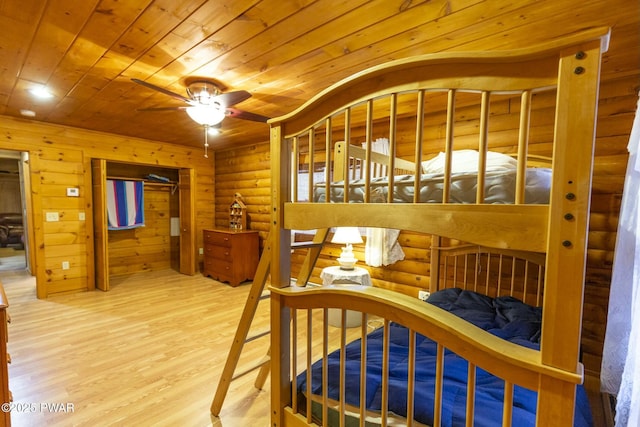 bedroom featuring hardwood / wood-style flooring, rustic walls, ceiling fan, and wood ceiling