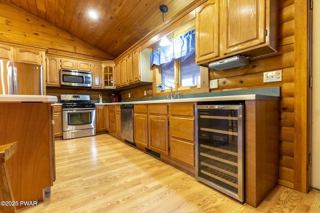 kitchen featuring beverage cooler, stainless steel appliances, light hardwood / wood-style flooring, decorative light fixtures, and vaulted ceiling