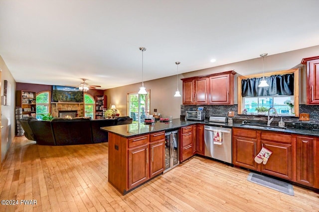 kitchen with kitchen peninsula, stainless steel dishwasher, beverage cooler, sink, and pendant lighting