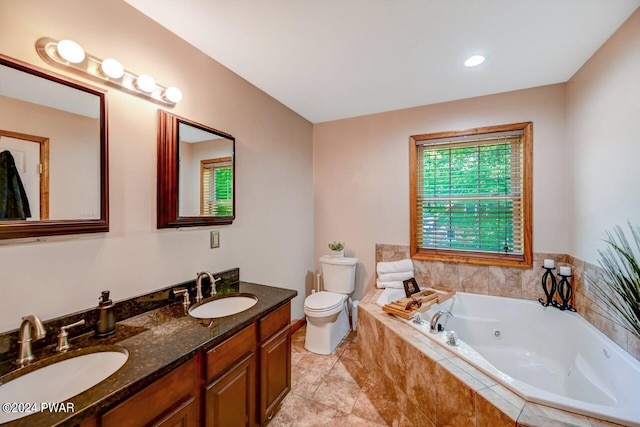 bathroom with vanity, tiled bath, and toilet