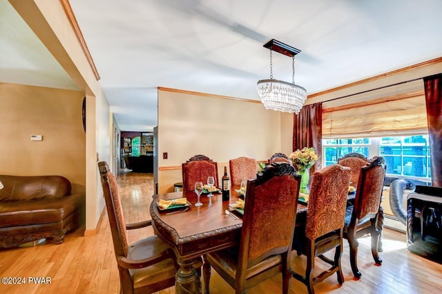 dining area with light hardwood / wood-style floors, crown molding, and an inviting chandelier