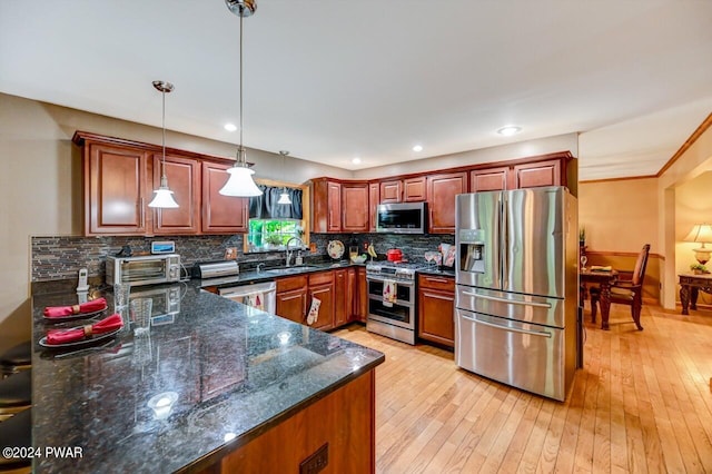 kitchen with dark stone counters, sink, decorative backsplash, decorative light fixtures, and stainless steel appliances