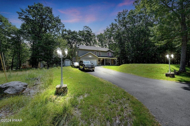 view of front of house featuring a lawn, a garage, and a storage shed