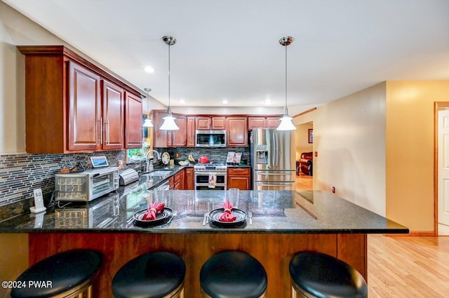 kitchen with a kitchen bar, kitchen peninsula, pendant lighting, and stainless steel appliances