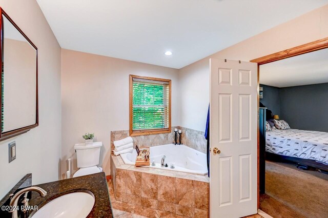 bathroom with vanity, a relaxing tiled tub, and toilet