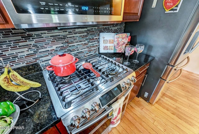 kitchen featuring backsplash, stainless steel appliances, hardwood / wood-style flooring, and dark stone counters