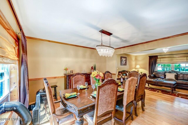 dining room with crown molding, light hardwood / wood-style flooring, and an inviting chandelier