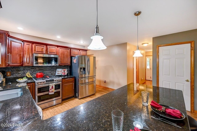 kitchen featuring appliances with stainless steel finishes, decorative light fixtures, tasteful backsplash, and sink