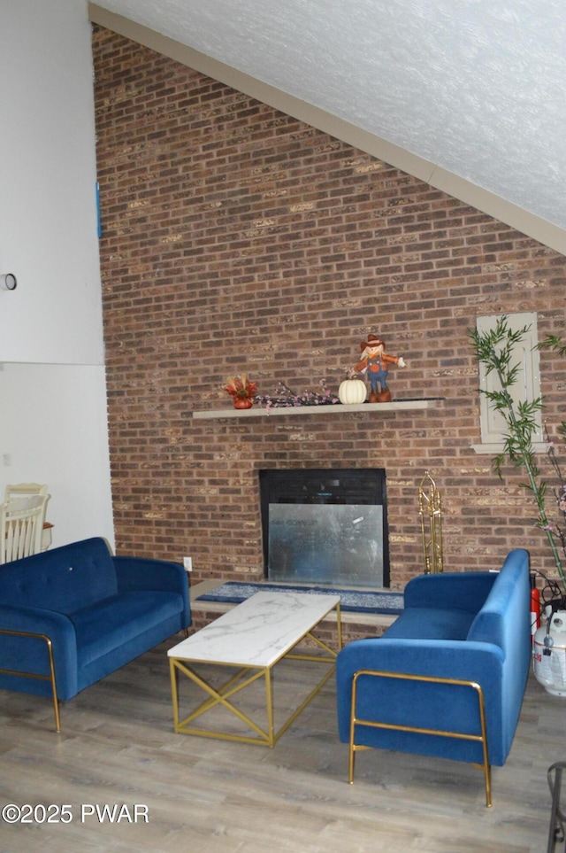 6372 Baltic Ave, Tobyhanna, PA 18466 - living area featuring high vaulted ceiling, brick wall, a fireplace, and wood finished floors