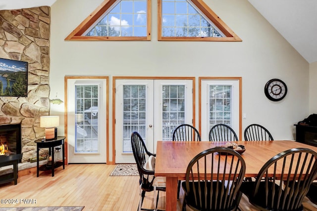 dining room with light hardwood / wood-style floors, lofted ceiling, a fireplace, and french doors