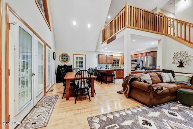 living room with light hardwood / wood-style floors, a towering ceiling, and french doors