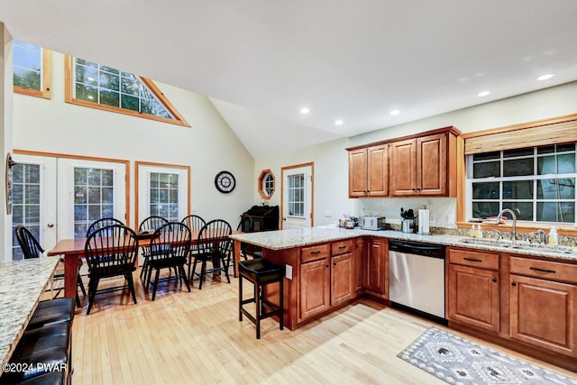 kitchen featuring a kitchen bar, kitchen peninsula, light stone countertops, sink, and dishwasher