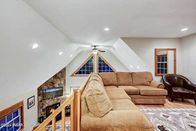 living room with ceiling fan, a fireplace, wood-type flooring, and lofted ceiling