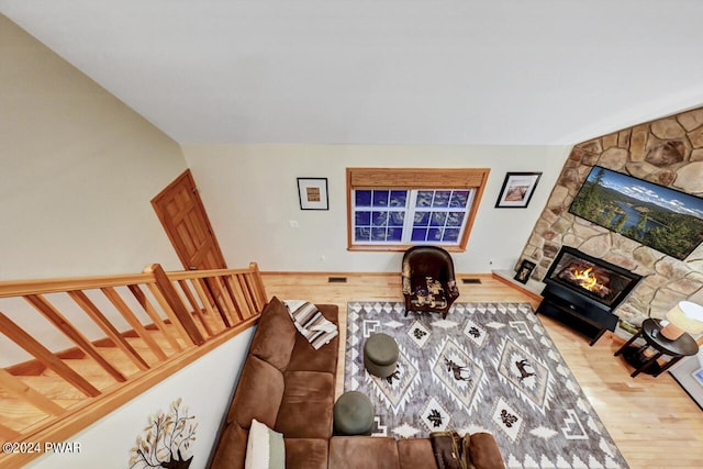 living room with wood-type flooring and a stone fireplace