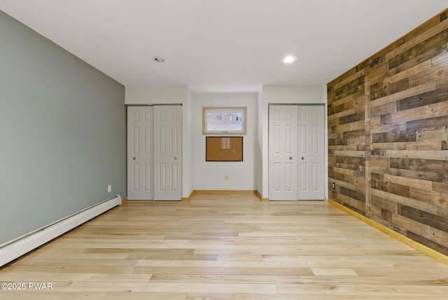 20 Chuck Foster Dr, Hawley, PA 18428 - unfurnished bedroom with two closets, baseboard heating, wood walls, light wood finished floors, and recessed lighting