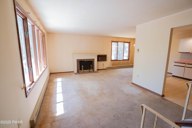 unfurnished living room with light colored carpet, a brick fireplace, baseboards, a baseboard radiator, and an AC wall unit