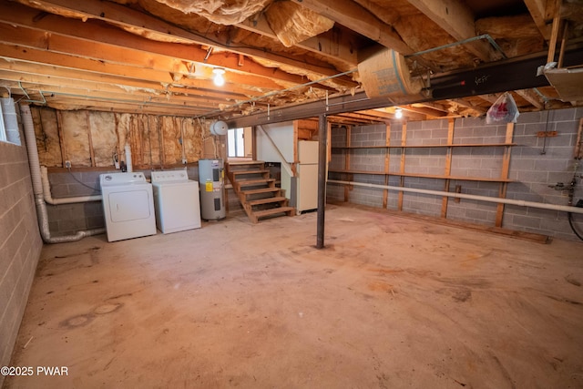unfinished basement with stairway, hybrid water heater, washing machine and dryer, and freestanding refrigerator