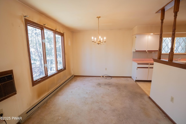 unfurnished dining area featuring light colored carpet, a chandelier, a baseboard heating unit, and a healthy amount of sunlight