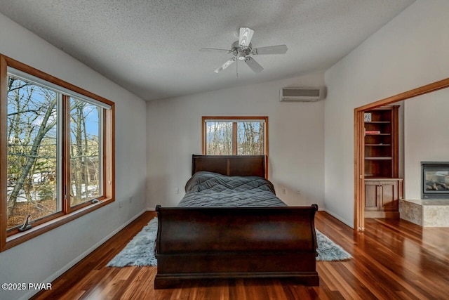 bedroom with lofted ceiling, a wall mounted air conditioner, dark hardwood / wood-style floors, and multiple windows