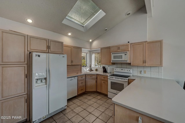 kitchen featuring lofted ceiling with skylight, light brown cabinetry, sink, white appliances, and decorative backsplash