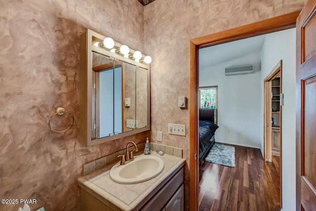 bathroom featuring vanity, hardwood / wood-style flooring, vaulted ceiling, and a wall mounted AC