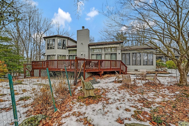 snow covered property featuring a deck and a sunroom