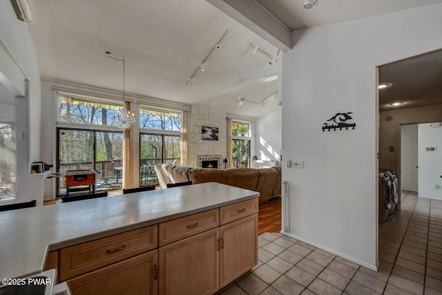 kitchen with pendant lighting, light tile patterned floors, a fireplace, and track lighting