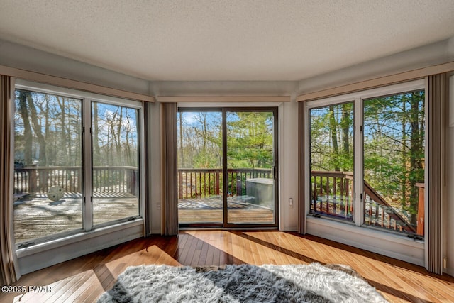 interior space with access to exterior, light hardwood / wood-style flooring, and a textured ceiling