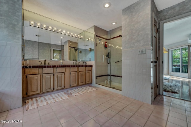 bathroom featuring tile patterned flooring, vanity, tile walls, and an enclosed shower