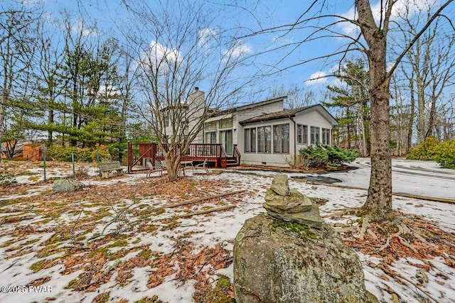 snow covered back of property featuring a deck