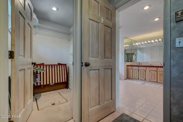 hallway with light tile patterned flooring and sink