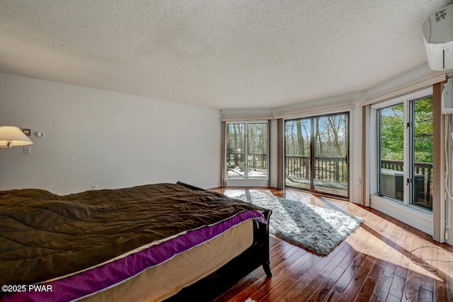 bedroom with hardwood / wood-style floors, a textured ceiling, and access to outside