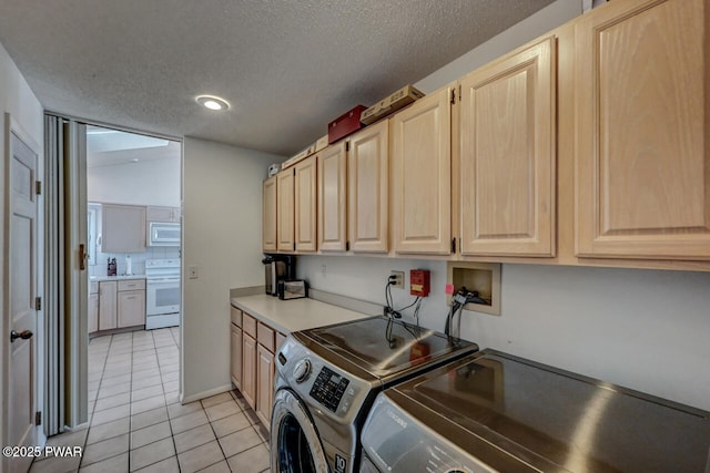 laundry area featuring separate washer and dryer, light tile patterned floors, cabinets, and a textured ceiling