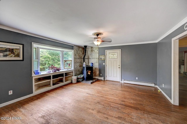 unfurnished living room featuring ornamental molding, ceiling fan, a baseboard radiator, hardwood / wood-style floors, and a wood stove