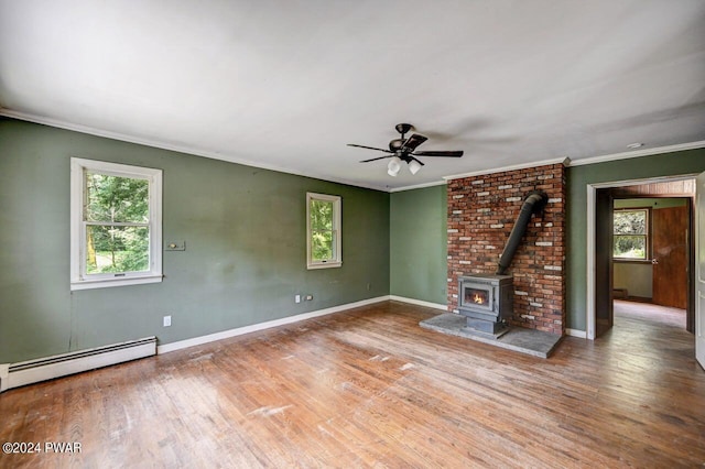 unfurnished living room with a wood stove, ceiling fan, baseboard heating, crown molding, and hardwood / wood-style floors