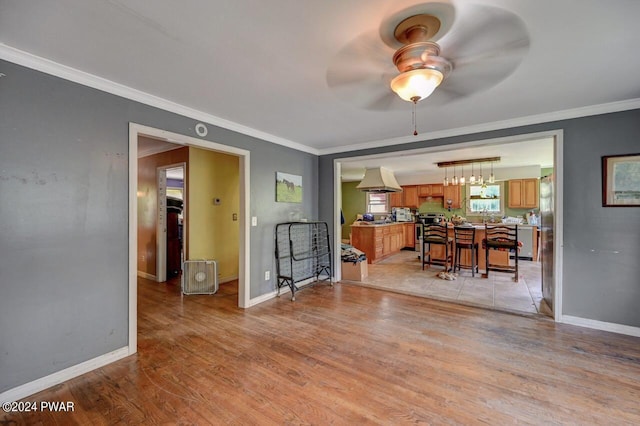 interior space with ceiling fan, light wood-type flooring, and ornamental molding