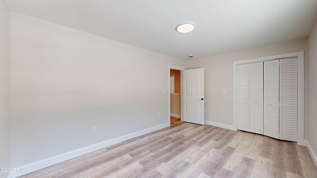 unfurnished bedroom with a closet and light hardwood / wood-style flooring