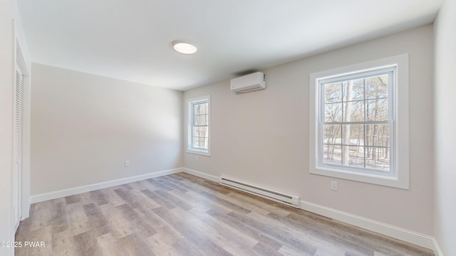 spare room featuring light wood-type flooring, a wall unit AC, and baseboard heating