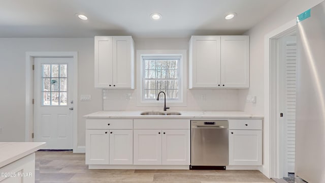 kitchen with sink, fridge, light stone countertops, white cabinets, and decorative backsplash