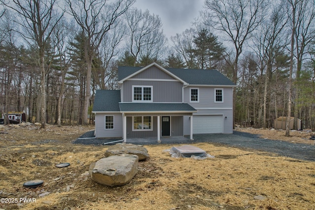 traditional-style home featuring driveway, a porch, an attached garage, and a shingled roof