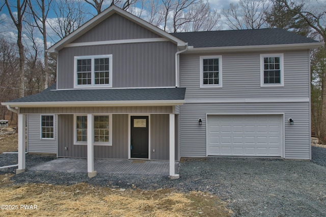 traditional home with a porch, an attached garage, driveway, and roof with shingles