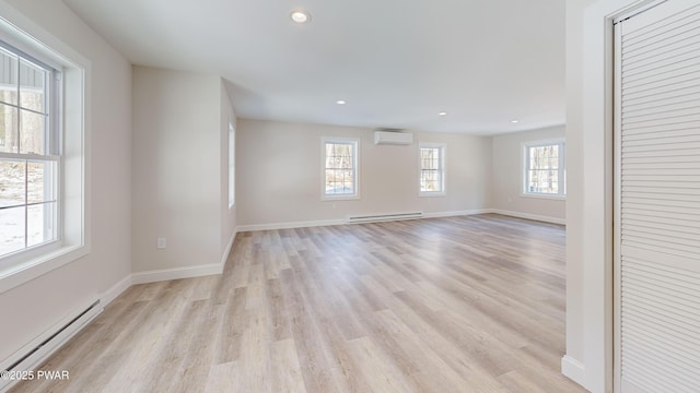 empty room with a baseboard radiator, a wall unit AC, and light hardwood / wood-style flooring