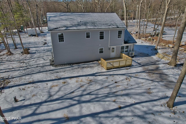 snow covered rear of property with a deck