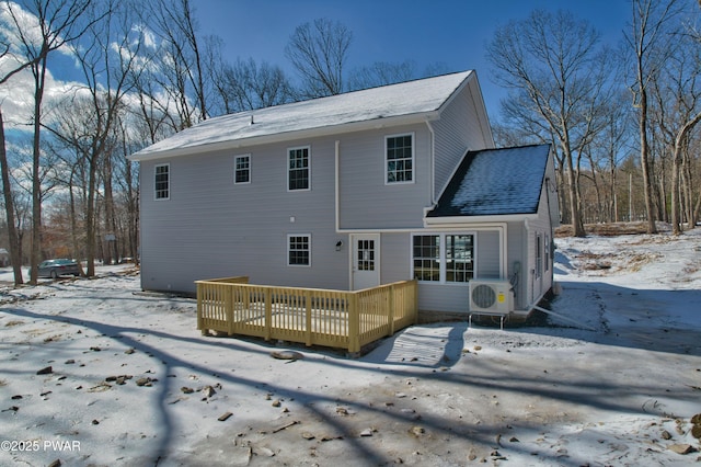 snow covered house with a wooden deck and ac unit