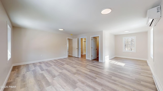 empty room with a wall mounted AC and light wood-type flooring