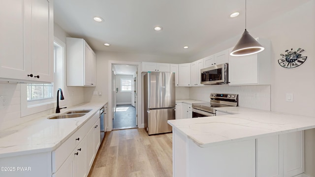 kitchen with appliances with stainless steel finishes, sink, pendant lighting, and white cabinets