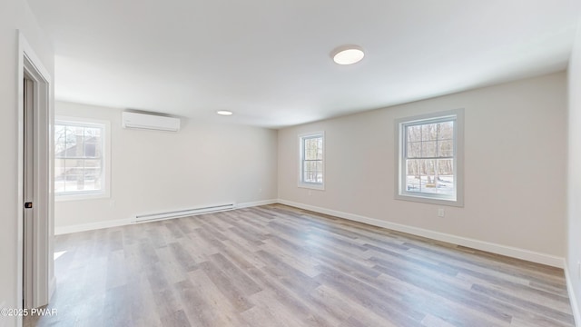 spare room with a baseboard radiator, a wall mounted air conditioner, and light hardwood / wood-style flooring