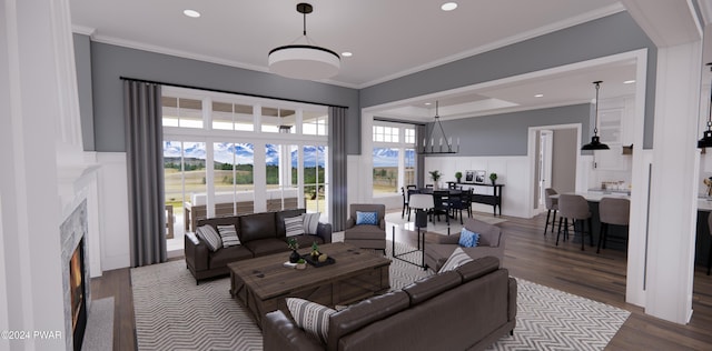 living room with hardwood / wood-style floors, a notable chandelier, crown molding, and a tiled fireplace